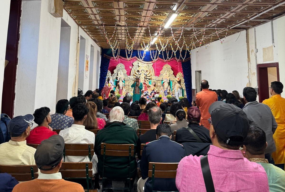 Durga Puja im Tempel: Die Gemeinde sitzt vor dem geschmückten Altar mit der Durga-Pratima